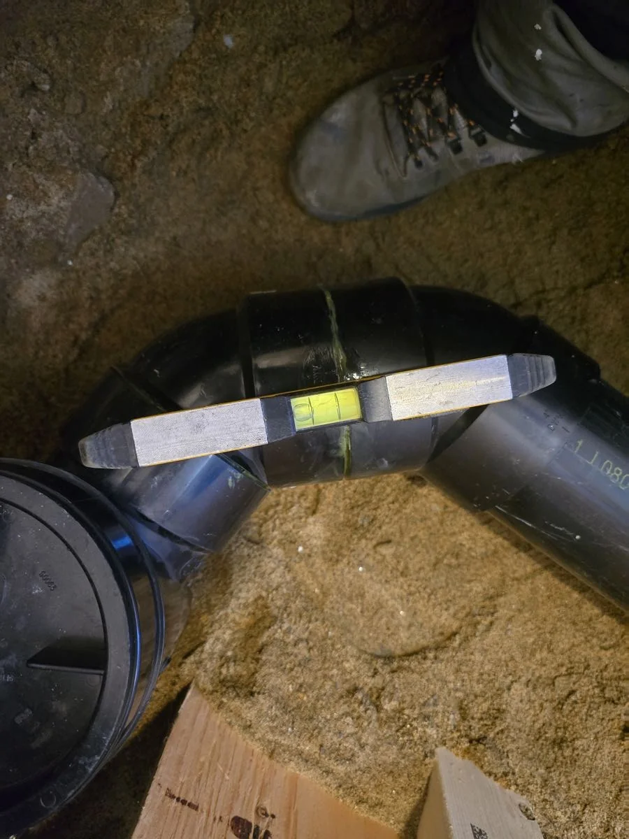 Drain line levelled and set before backfill beneath a home