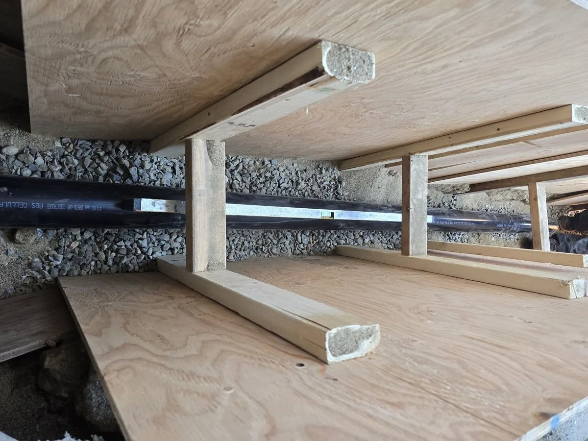 Completed drain and vent piping run through a framed floor