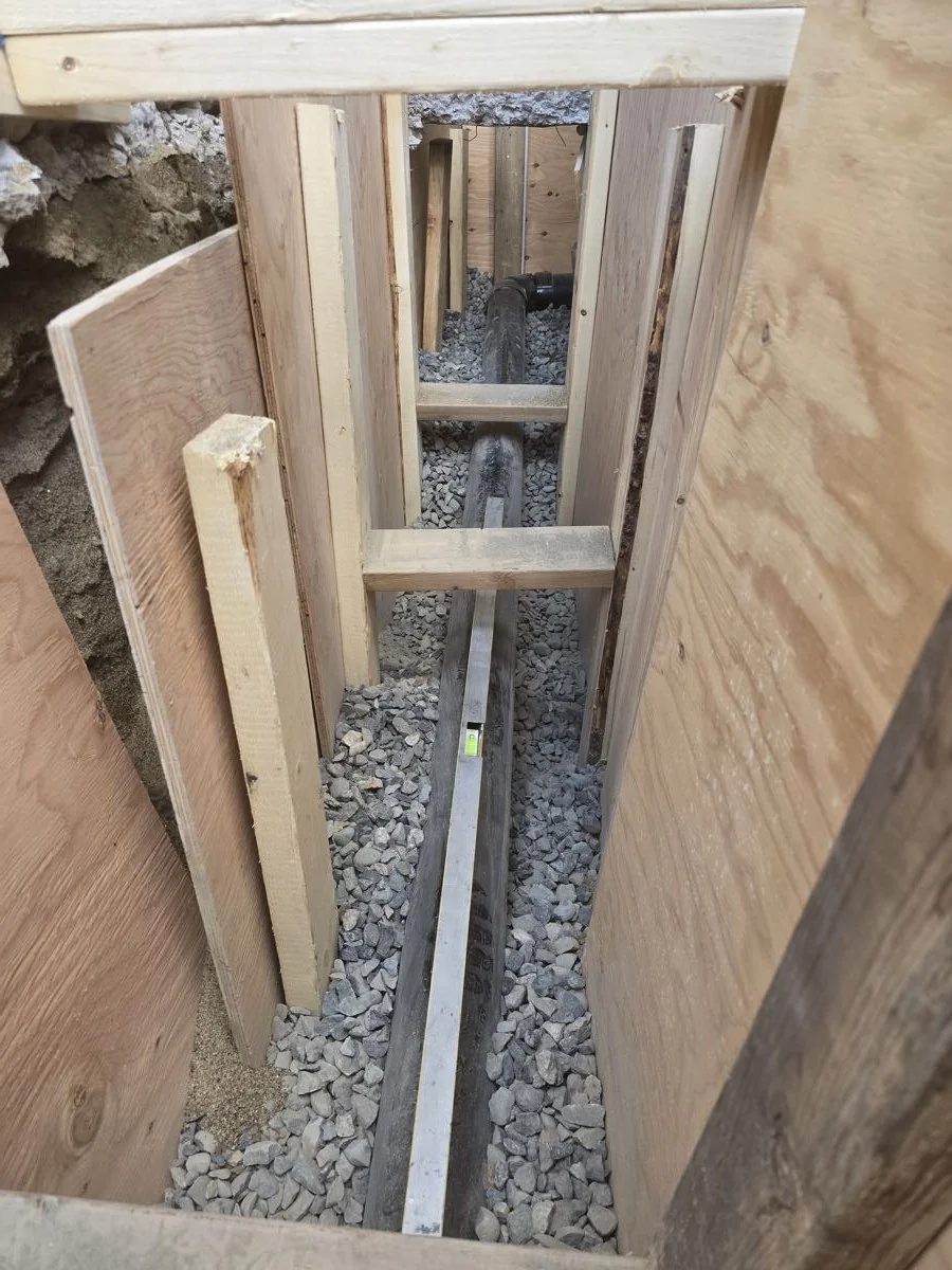 Shored trench with new drain line run beneath a building