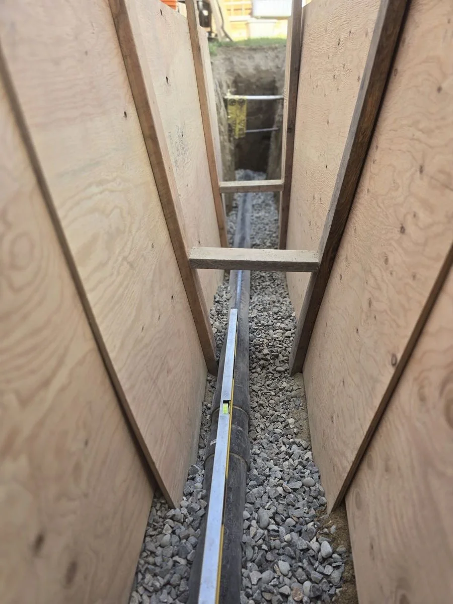 New underground drain line laid the full length of a shored trench