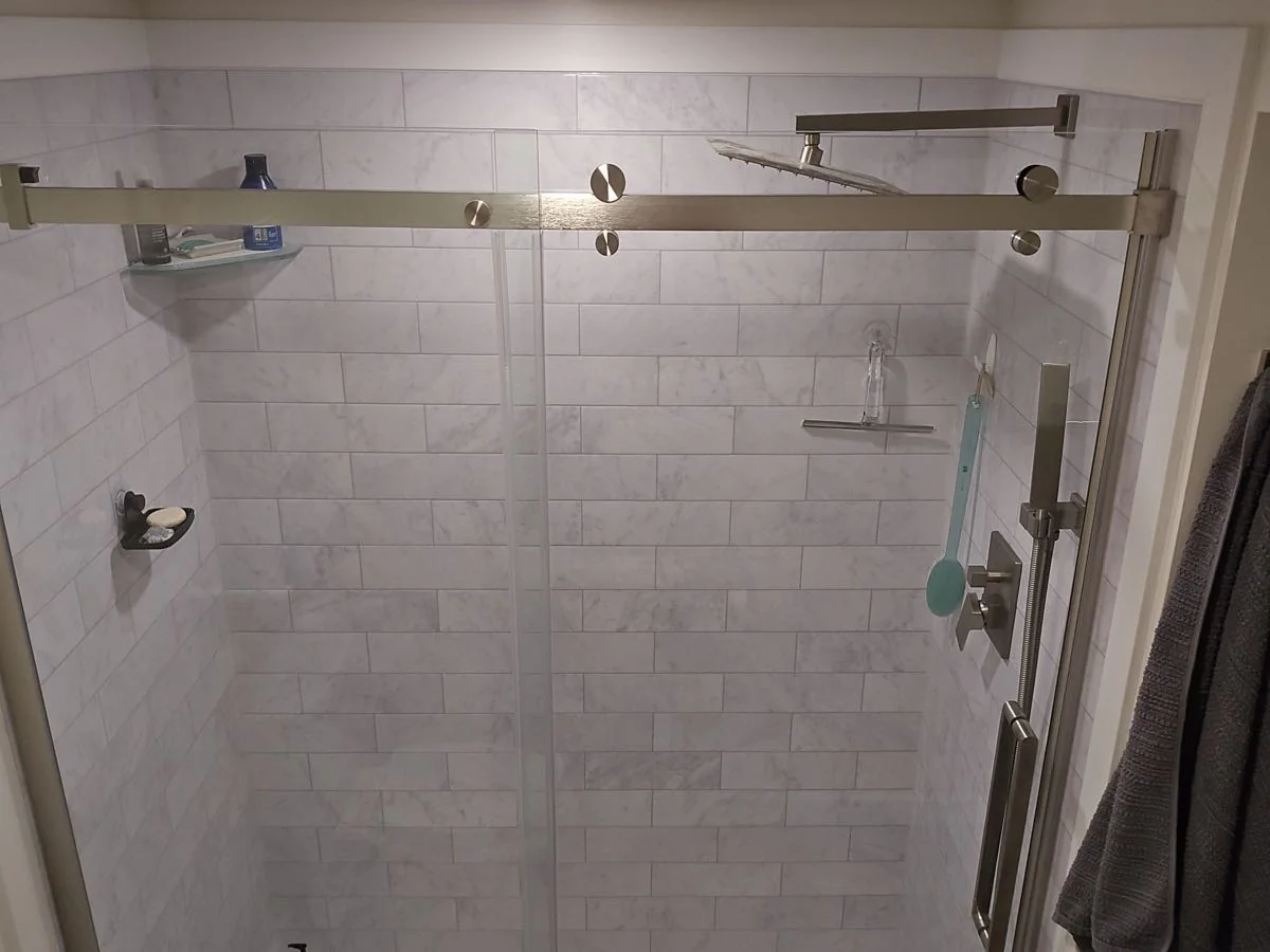 Subway tiled shower with brushed fixtures and glass panel