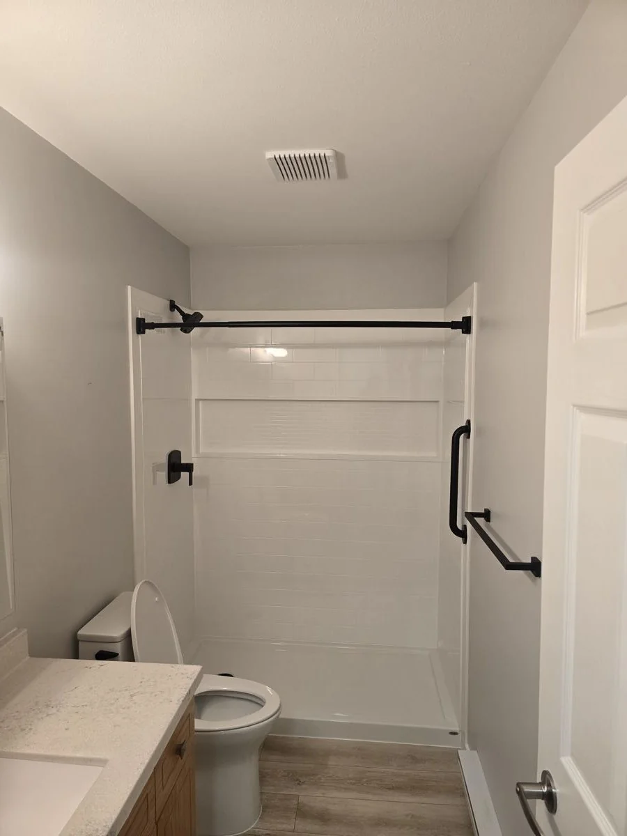 Finished bathroom with white shower surround and black fixtures