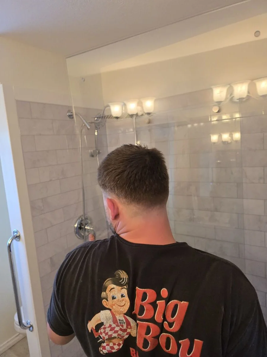 Shower tiling in progress with vanity lighting installed